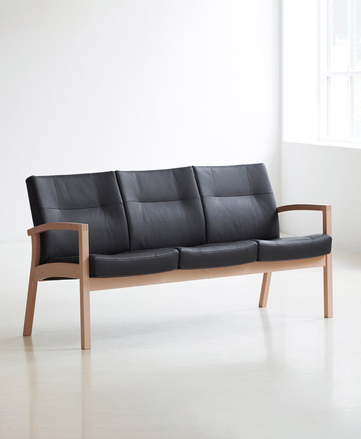 3-personers sofa, model Scala 5413, stel i natur bøg og polster i sort læder, set fra skrå i lyst miljø.